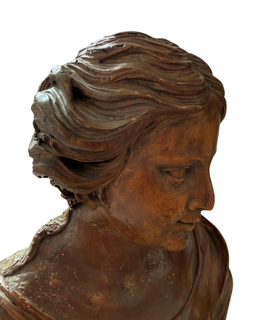 Close-up profile of the carved wooden bust's face and flowing hair, head turned and gazing downward
