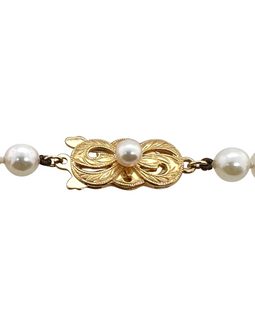 Front view of Mikimoto’s 18K gold clasp designed in a bow shape with engraved leaf motifs and a central pearl, showcasing elegant Japanese craftsmanship.