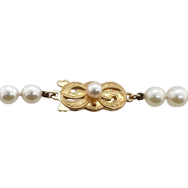 Front view of Mikimoto’s 18K gold clasp designed in a bow shape with engraved leaf motifs and a central pearl, showcasing elegant Japanese craftsmanship.