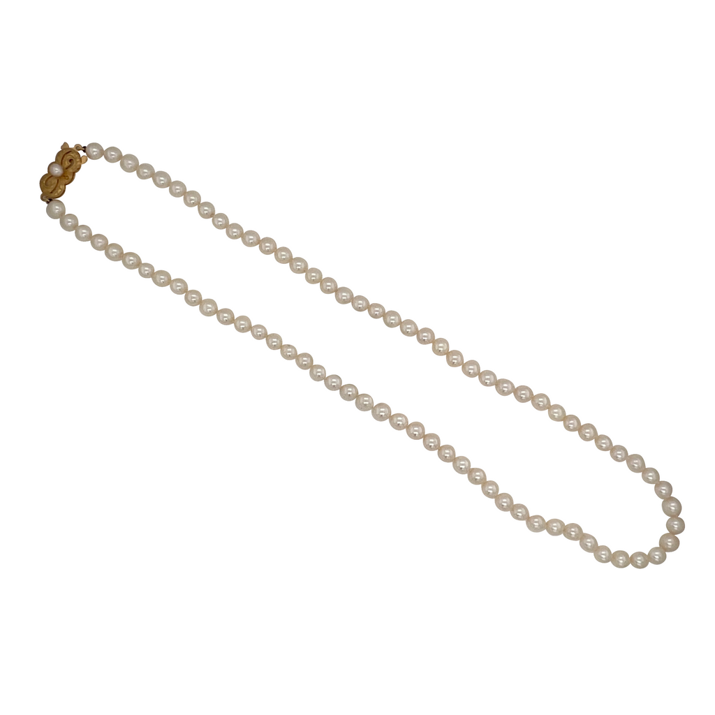 Full view of Mikimoto Akoya cultured pearl necklace with 5 mm pearls and 18K gold clasp, elegantly coiled to show luster and length.