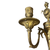Close‑up of an 18th‑century French Louis XVI gilt bronze sconce arm with floral and leaf motifs, showing the relief‑decorated candle socket and tulip‑form mount.