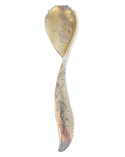 A silver spoon with ornate designs on the handle, displaying a mix of silver and white tones.