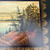 Detailed painted landscape on vintage tray showing rocky shoreline, evergreen trees, and distant hills within a gold leaf border.