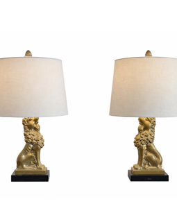 Pair of mid‑century patinated metal table lamps with seated gold lion bases on black plinths and beige drum shades.