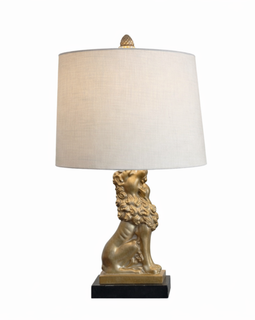Mid‑century table lamp with a gold patinated seated lion base on a black plinth and a beige drum lampshade with pinecone finial.