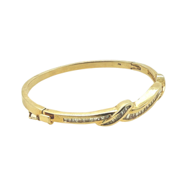 side view of a vintage 14K yellow gold bangle bracelet with channel-set baguette diamonds in an undulating ribbon design