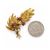 view of vintage 18K yellow gold leaf spray brooch with three ruby and sapphire flowers next to a quarter for scale